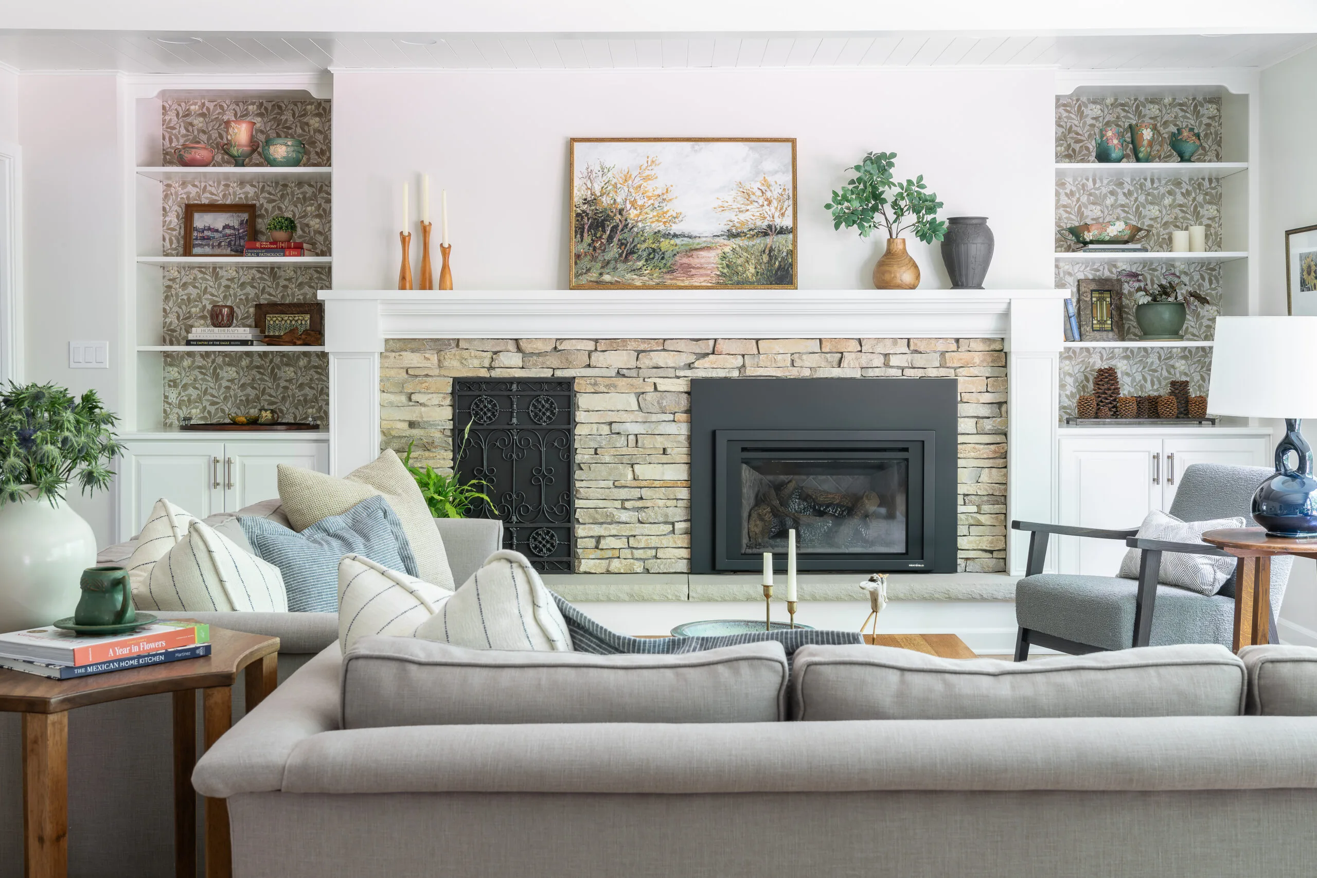 cozy living room with layered artwork and stone fireplace