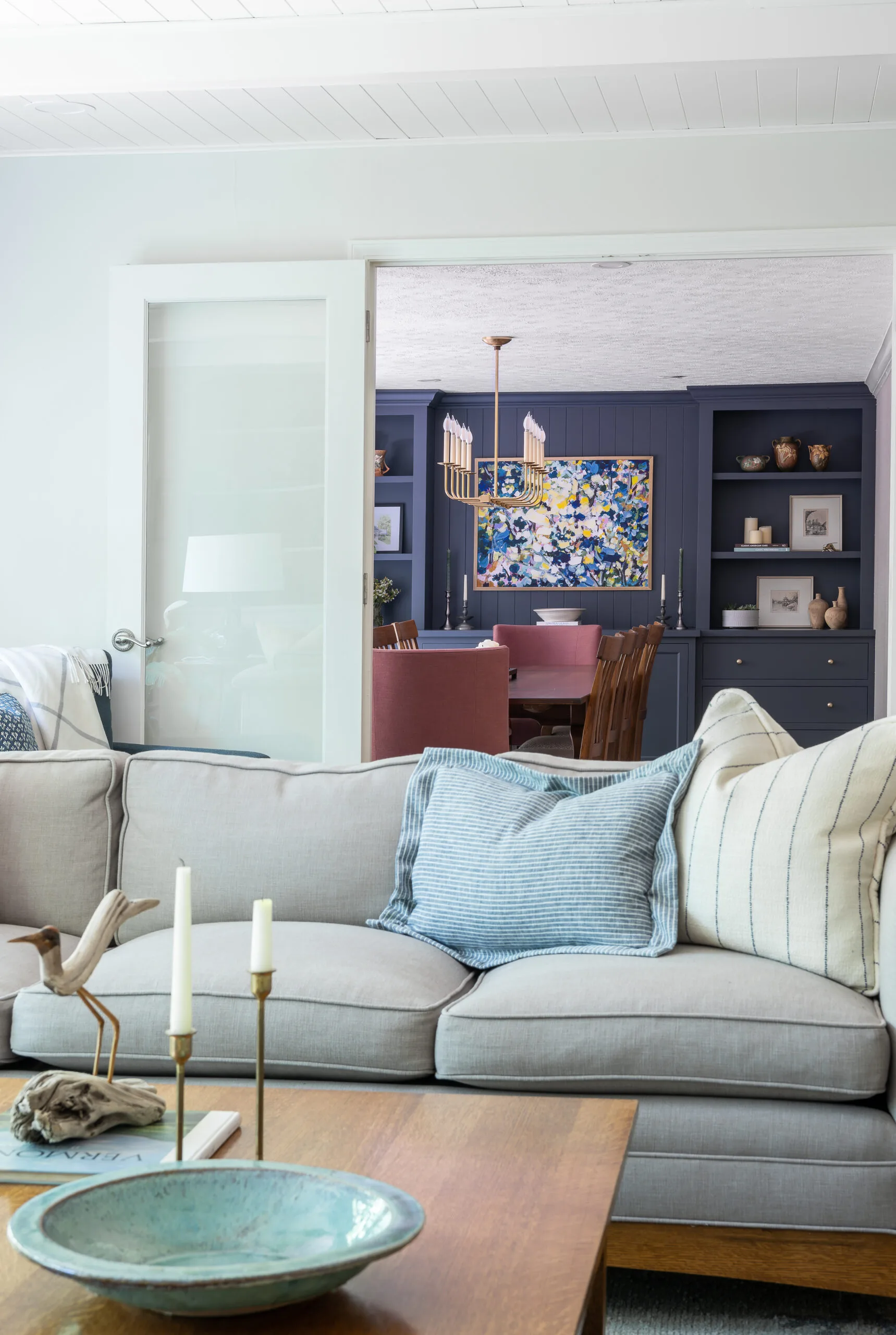 cozy sofa with custom pillow and craftsman coffee table with dining room in the distance with pop of blue cabinetry