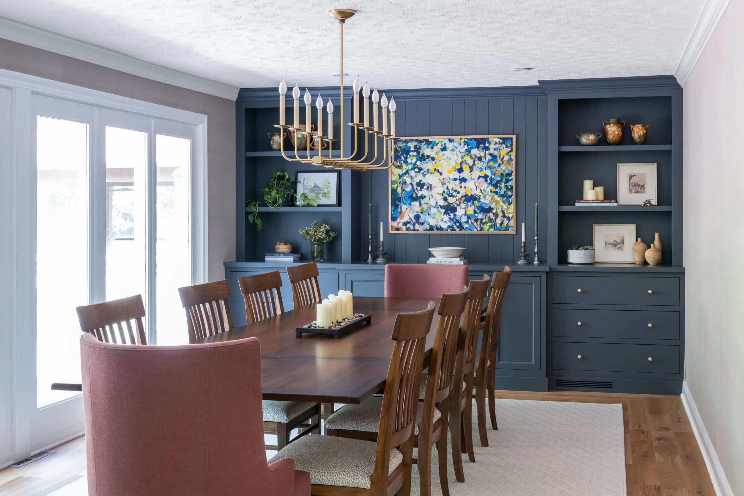classic dining room features with painted blue built in cabinetry and art focal piece with linear clean chandelier