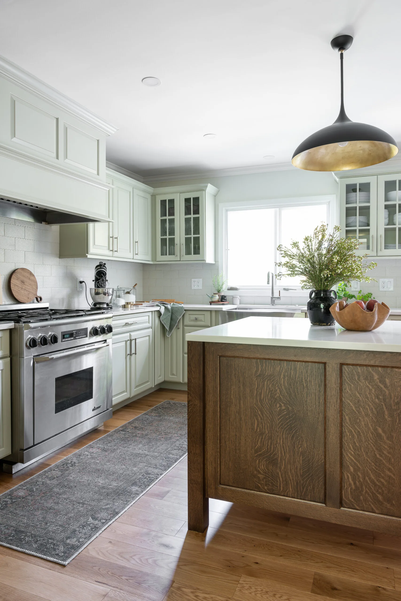 Craftsman style island in cozy kitchen with modern pendant and patterned rug