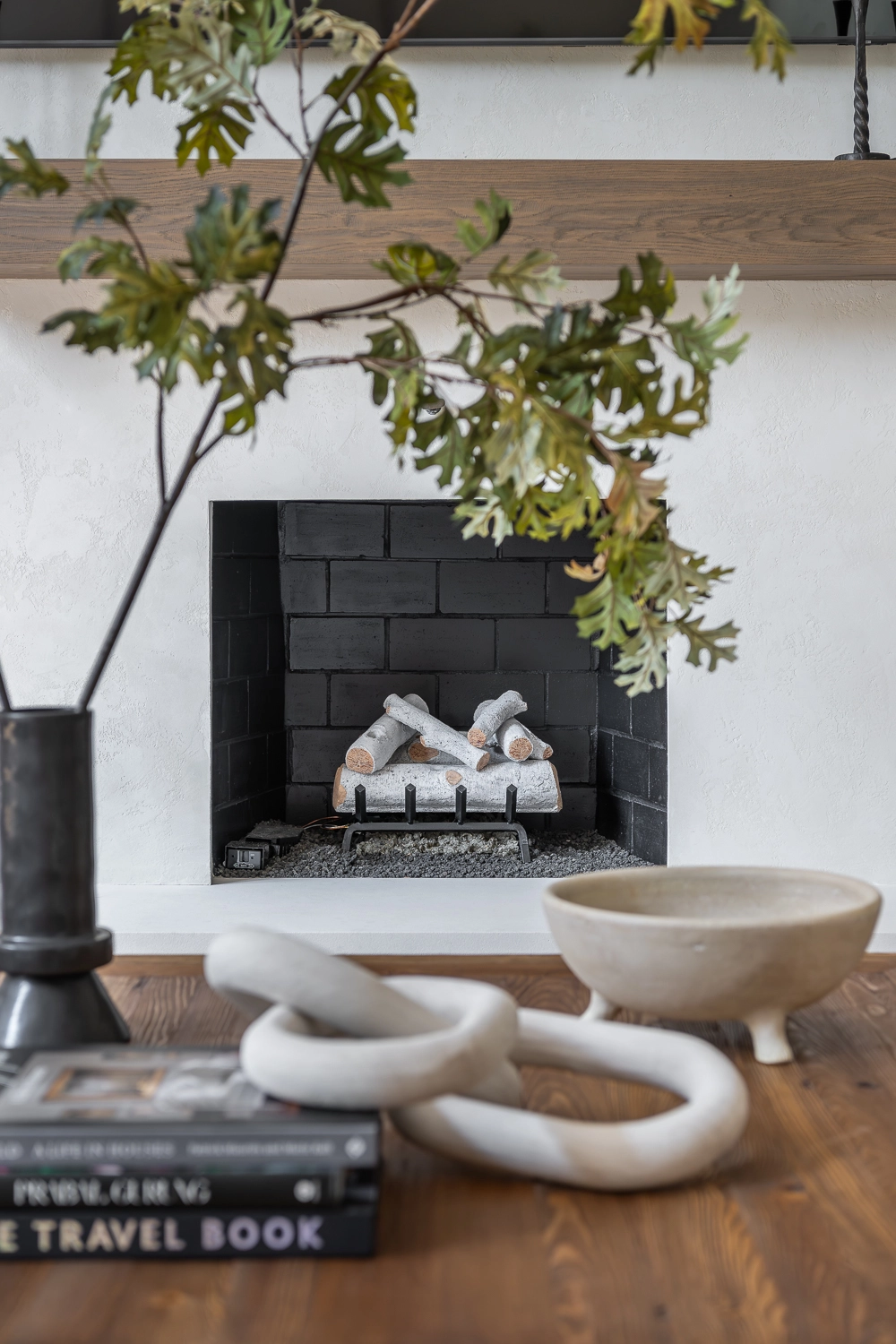 Fireplace with plaster surround and floating white oak mantle and birch logs