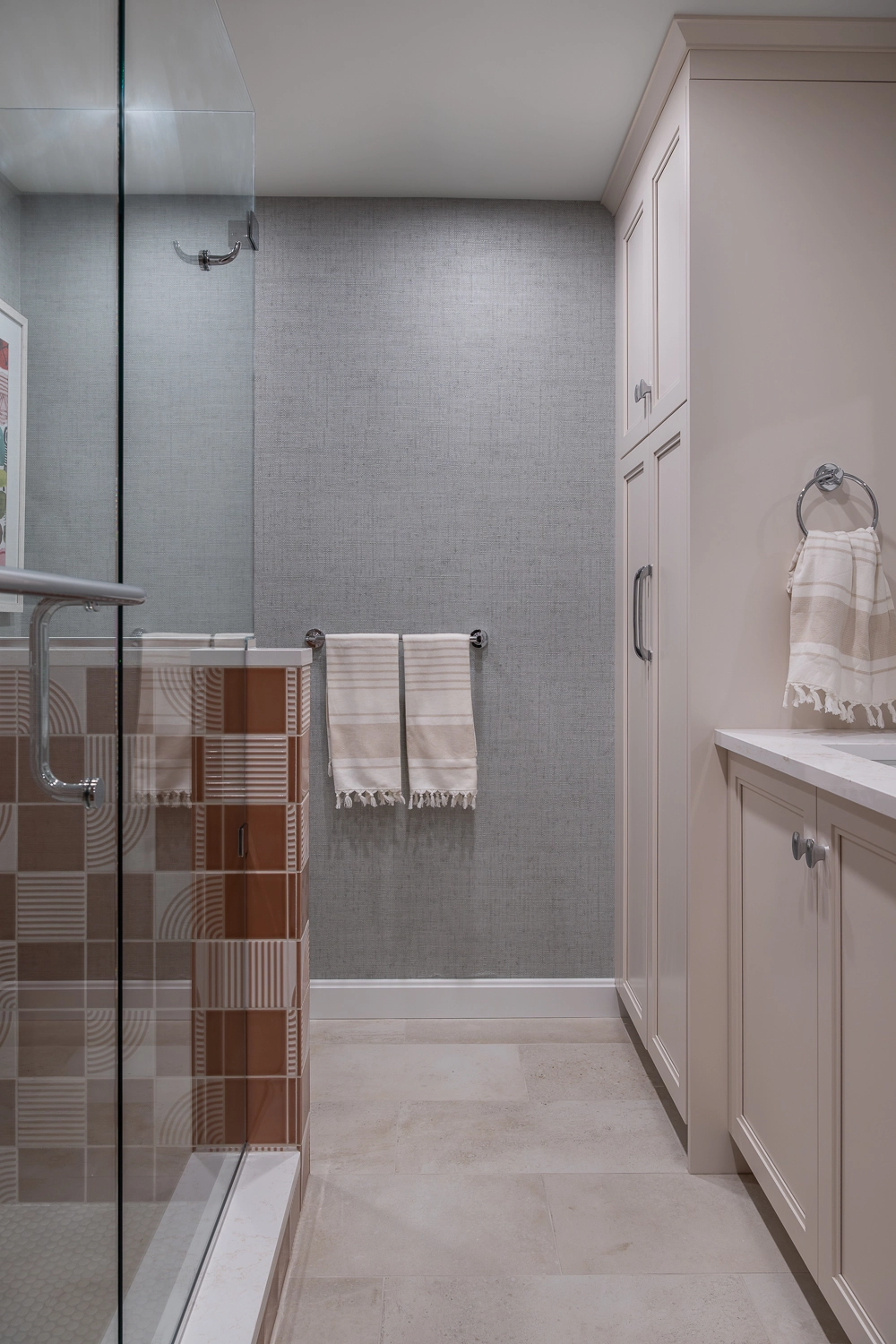 image of guest bathroom with coral tile shower in modern pattern and simple cabinetry with blue green grasscloth wallpaper on walls