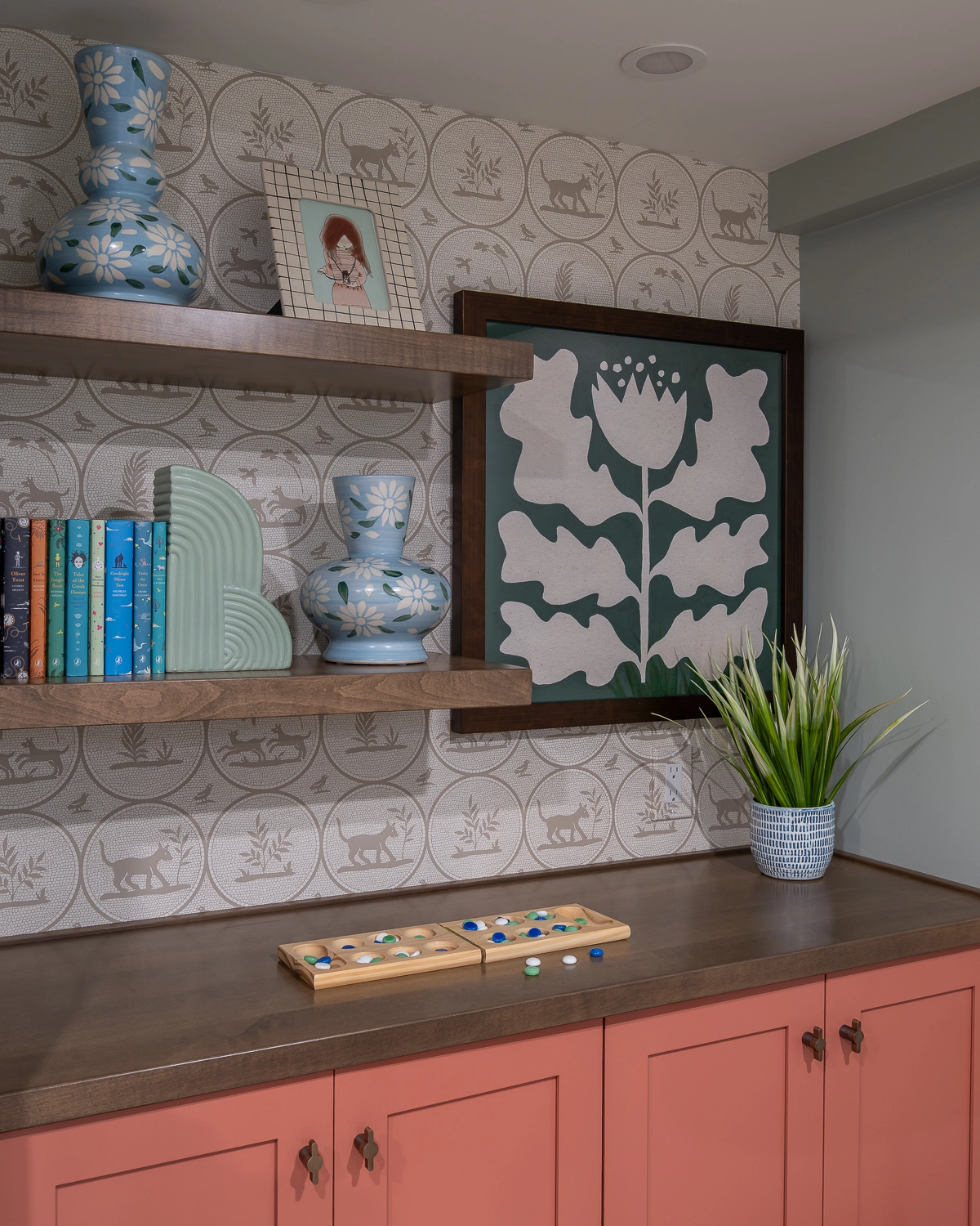 Colorful and inviting family living room with blue terazzo tile surround and coral cabinetry with playful wallpaper above base cabinets. Comfortable furniture