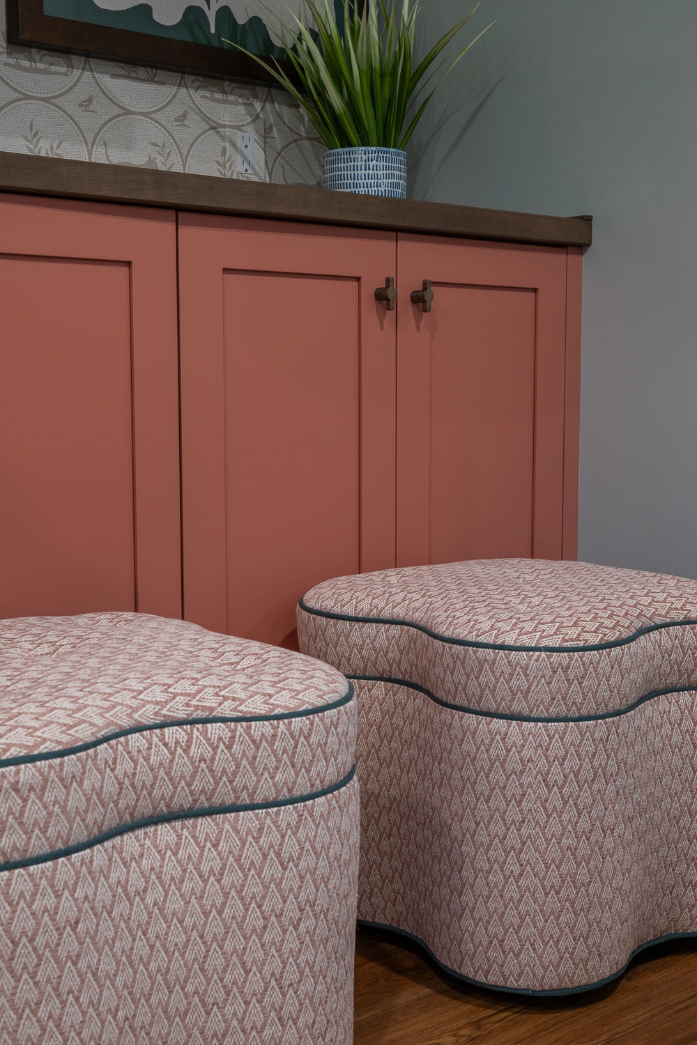 coral cabinetry with two ottoman upholstered in pink fabric sitting in front