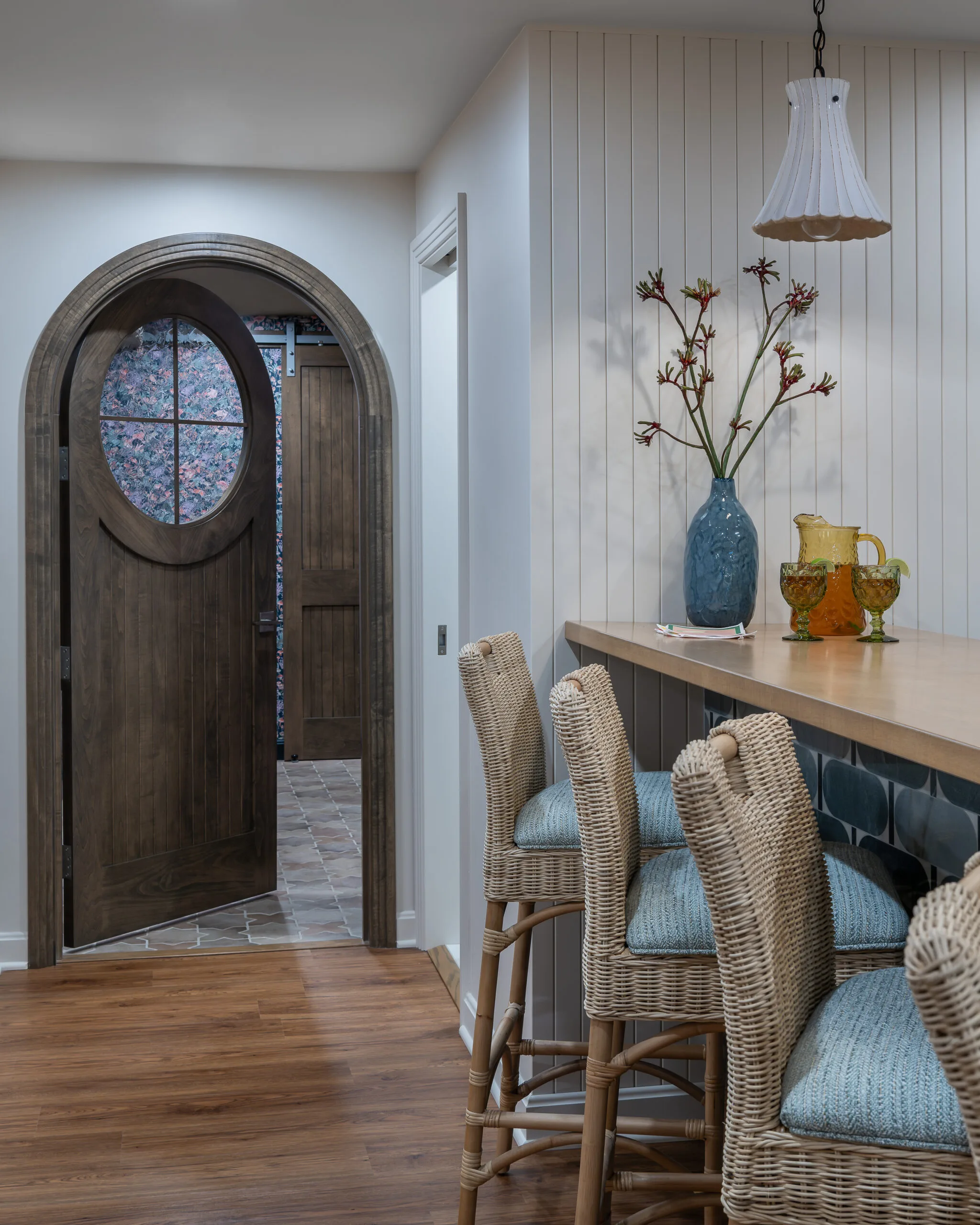 image of lower level bar looking at beauiful wooden arch doorway into the wine room, rattan chairs and stained bar top