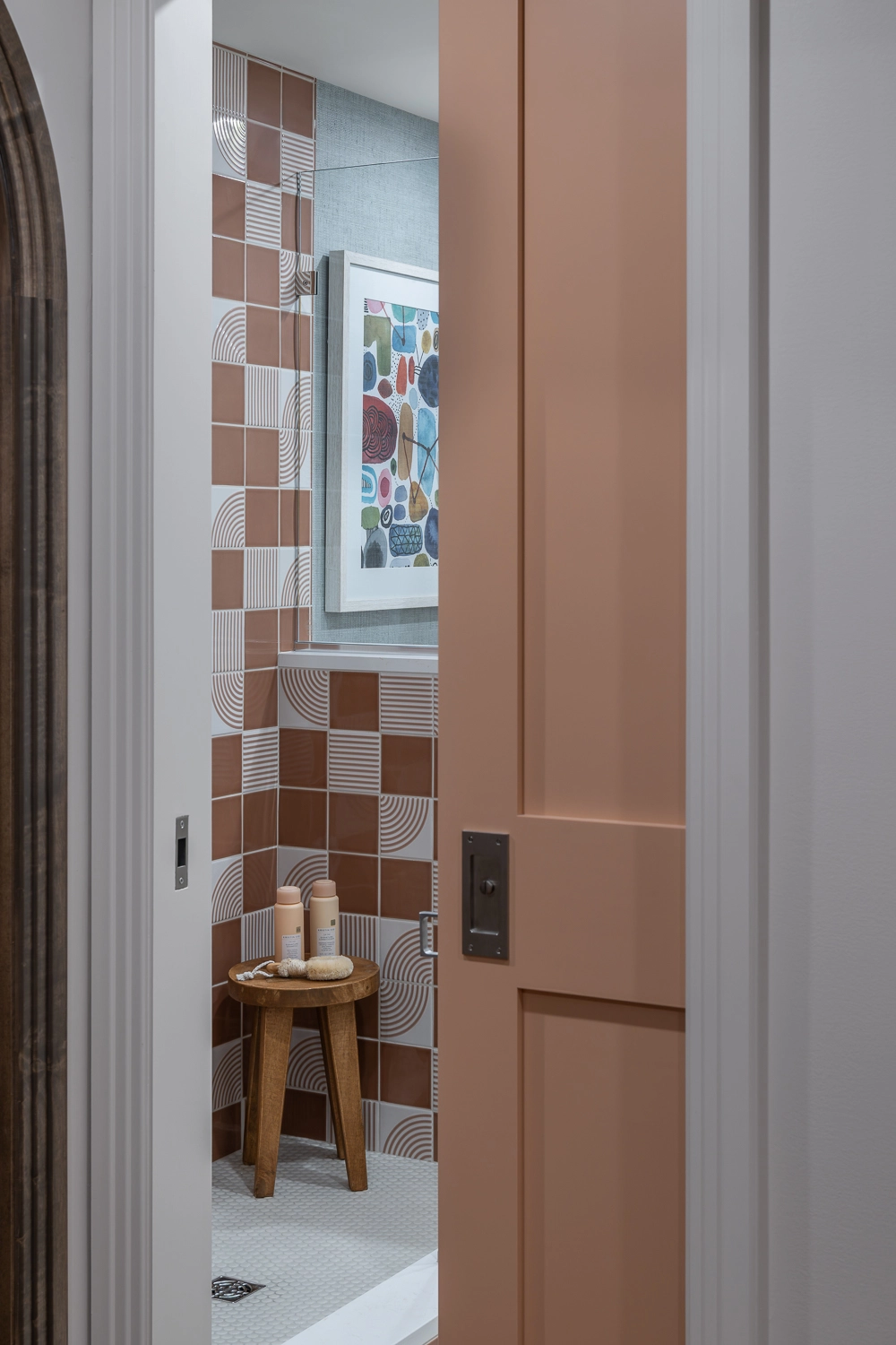 coral pocket door slightly open to guest bathroom with a peek at the coral modern tile shower
