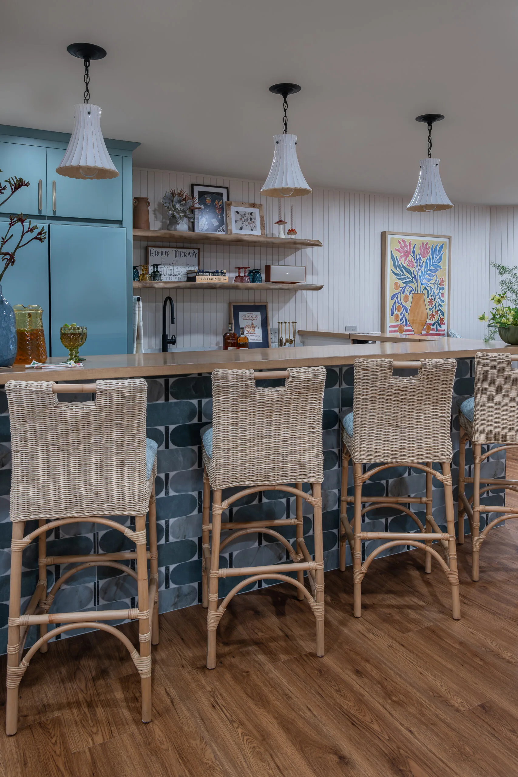 Lower Level playful bar with rattan coutnertsools and decorative penants with white shade and stained wood countertop