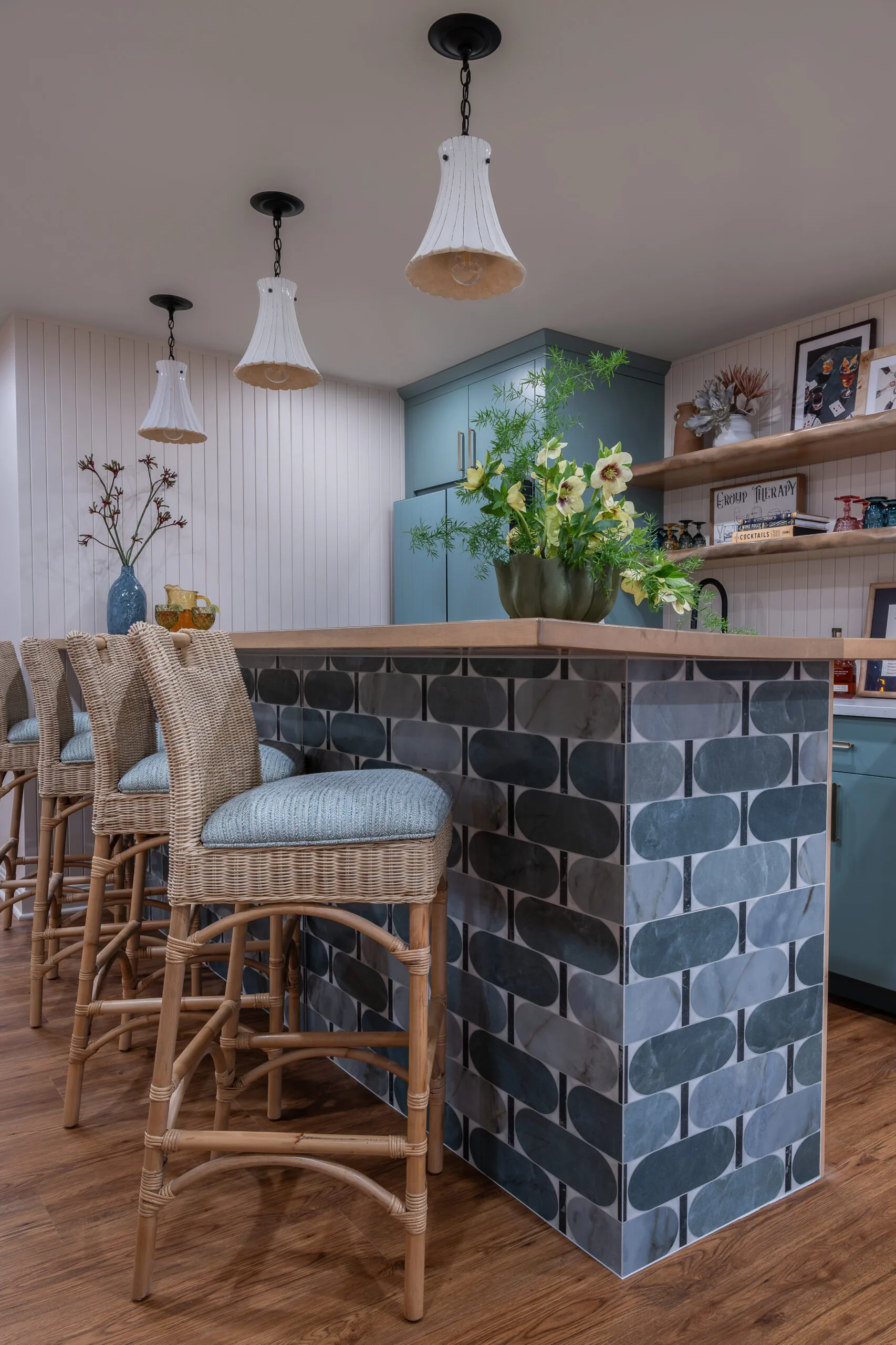 Lower Level playful bar with rattan coutnertsools and decorative penants with white shade and stained wood countertop