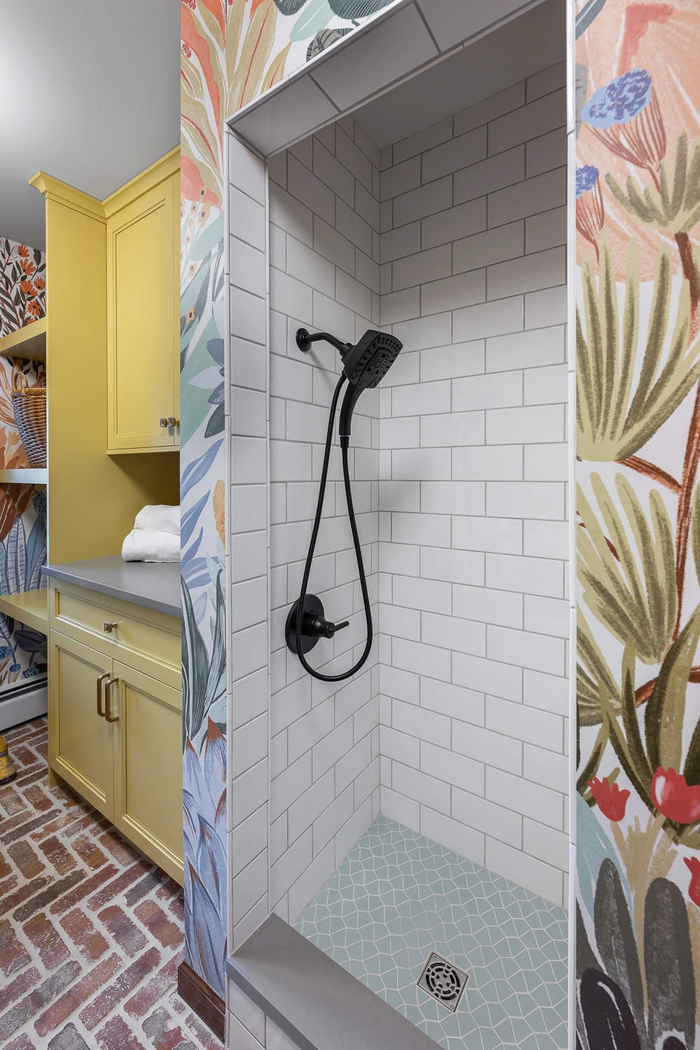 Colorful laundry room with large foliage wallpaper and golden yellow cabinetry and dog was