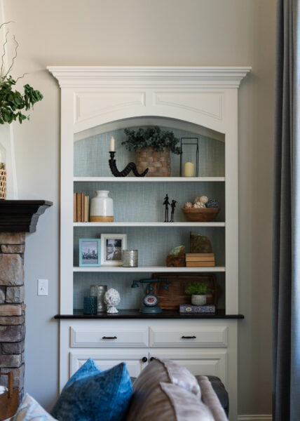 Living room built in book shelf with blue grasscloth background